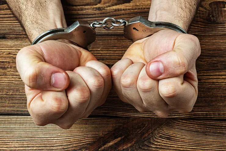 manos-esposadas-madera-oscura_157402-1687